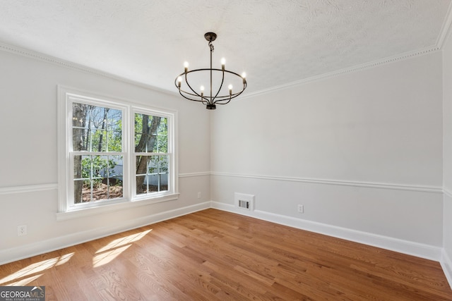 unfurnished dining area with a chandelier, a textured ceiling, wood finished floors, visible vents, and baseboards