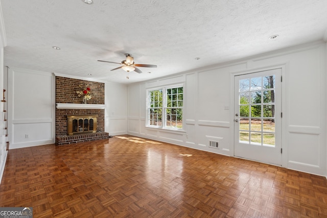 unfurnished living room featuring a textured ceiling, crown molding, a fireplace, and a decorative wall