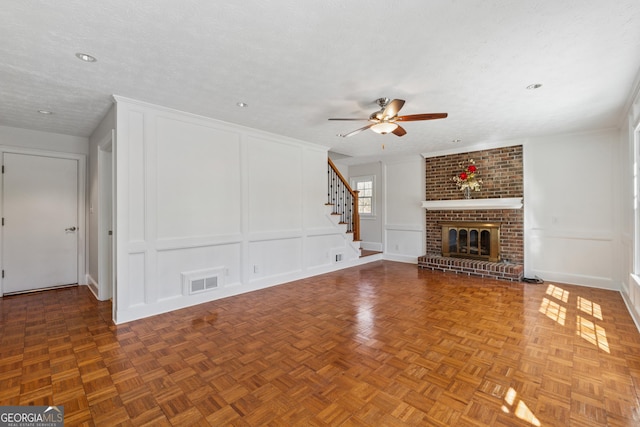 unfurnished living room with a textured ceiling, a decorative wall, a fireplace, visible vents, and stairway