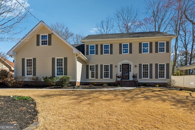 colonial home with fence and a front lawn