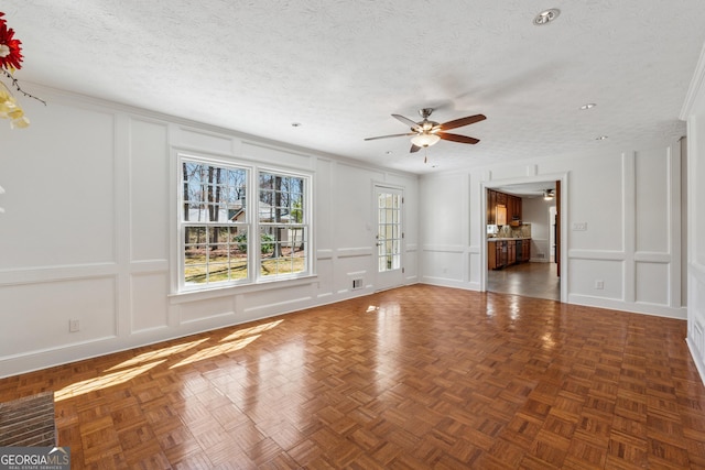 unfurnished living room featuring a ceiling fan, visible vents, a decorative wall, and a textured ceiling