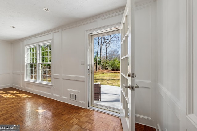 doorway featuring a textured ceiling, a decorative wall, and a wealth of natural light