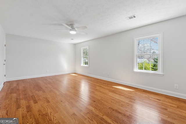 spare room with visible vents, a ceiling fan, a textured ceiling, light wood-type flooring, and baseboards