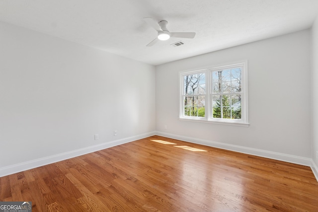 unfurnished room featuring baseboards, visible vents, ceiling fan, and light wood finished floors