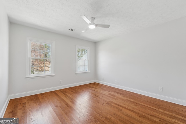 spare room featuring light wood finished floors, visible vents, and baseboards