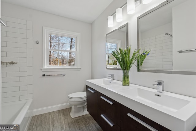 bathroom featuring wood finished floors, a sink, toilet, and baseboards