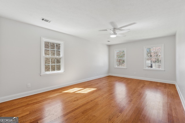 empty room with a ceiling fan, light wood-type flooring, visible vents, and baseboards