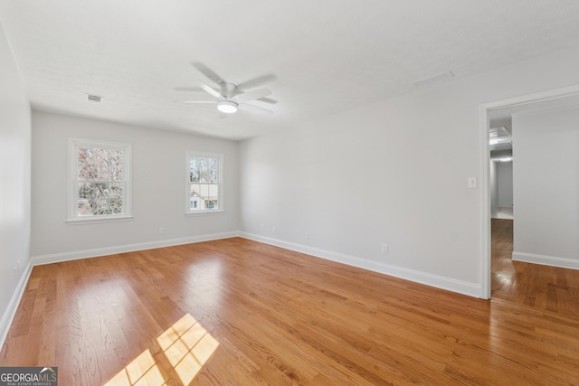 unfurnished room featuring light wood-style floors, baseboards, visible vents, and a ceiling fan