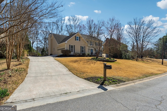 view of front of home featuring concrete driveway, a front lawn, and an attached garage