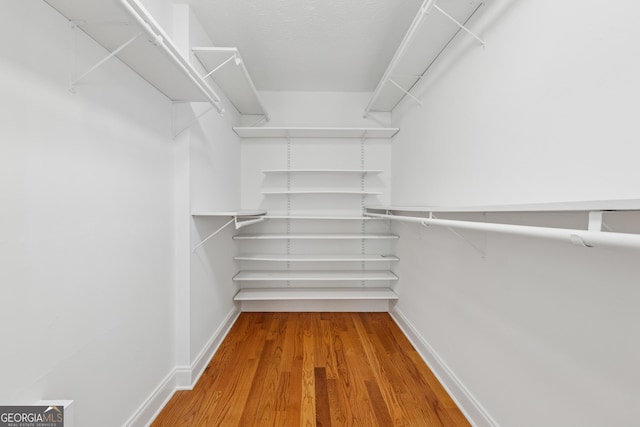 walk in closet with wood finished floors