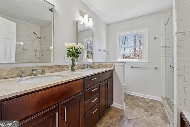 full bath featuring double vanity, a sink, toilet, and a shower stall