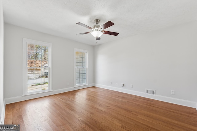 unfurnished room featuring baseboards, visible vents, ceiling fan, and wood finished floors