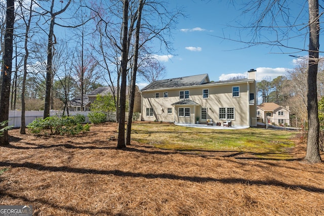 back of house featuring a yard, a chimney, a patio area, and fence