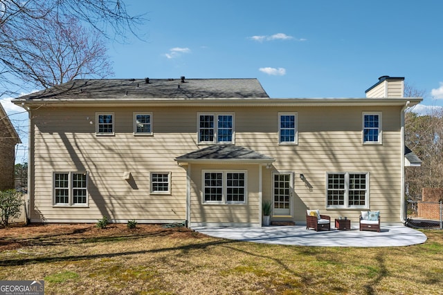 rear view of property featuring fence, a patio, a chimney, and a lawn