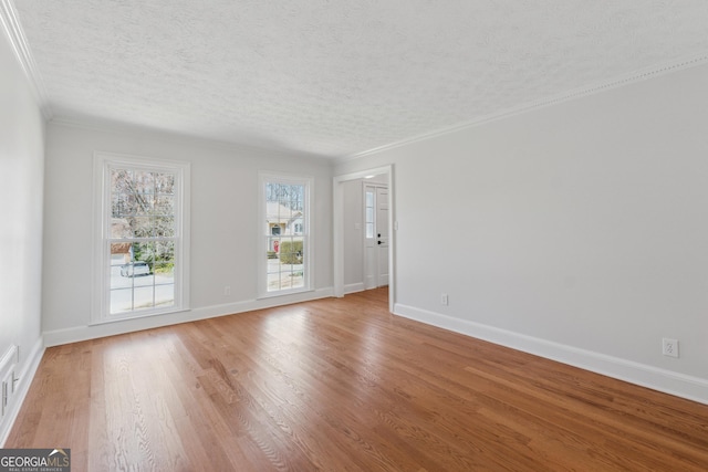 interior space featuring light wood-type flooring, crown molding, baseboards, and a textured ceiling