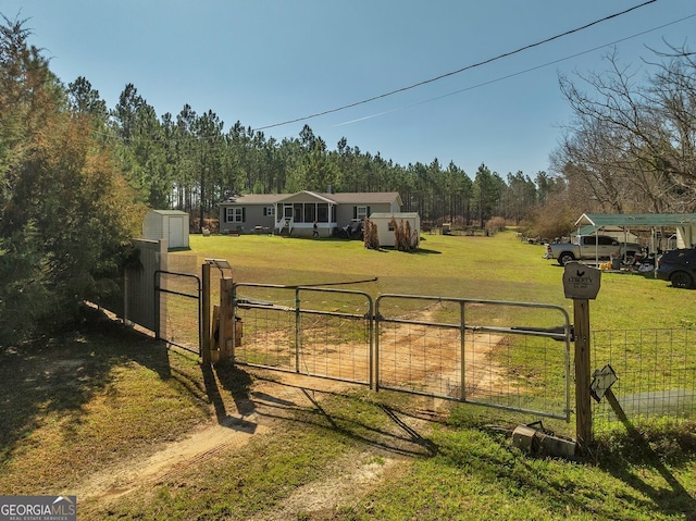 view of gate with an outbuilding, a yard, a shed, and fence