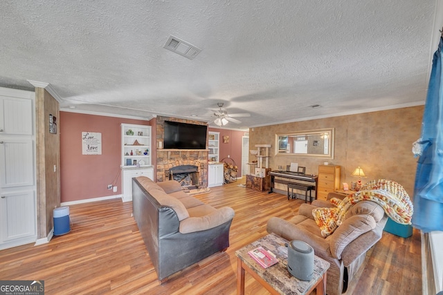 living room with a stone fireplace, light wood-style flooring, visible vents, and crown molding