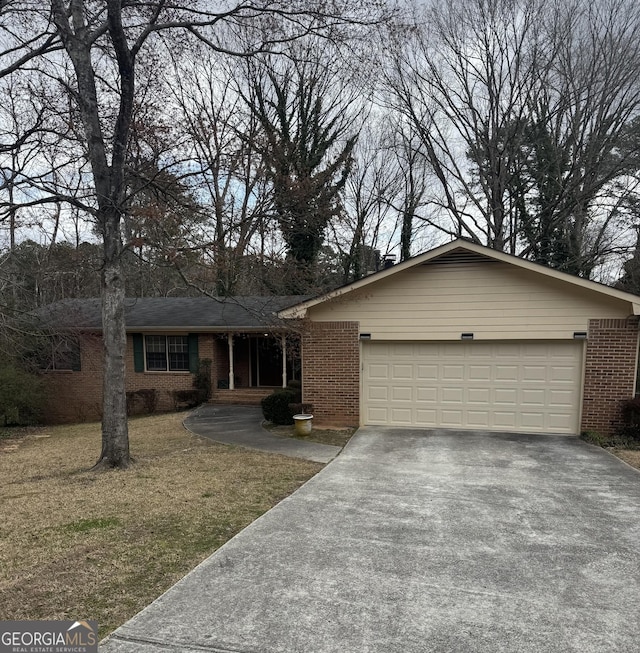 ranch-style home featuring driveway, brick siding, an attached garage, and a front yard