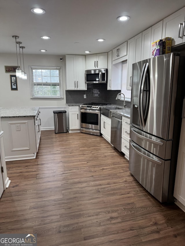 kitchen featuring dark wood-style flooring, white cabinetry, appliances with stainless steel finishes, backsplash, and light stone countertops