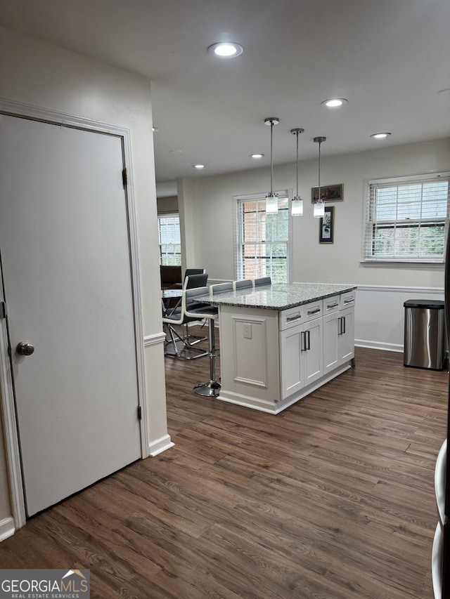 kitchen featuring light stone counters, decorative light fixtures, recessed lighting, dark wood-type flooring, and white cabinets