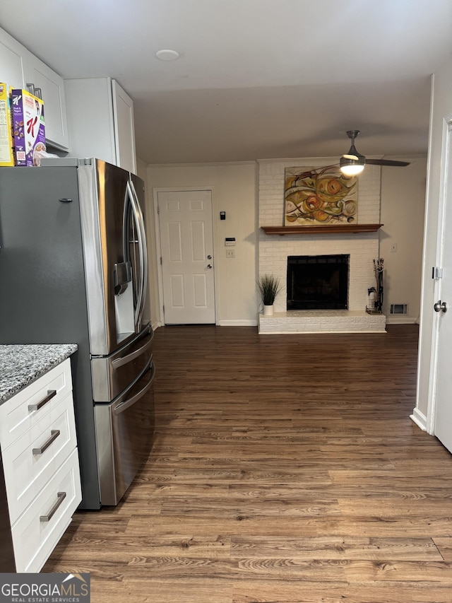 kitchen with stainless steel fridge, a fireplace, visible vents, and wood finished floors