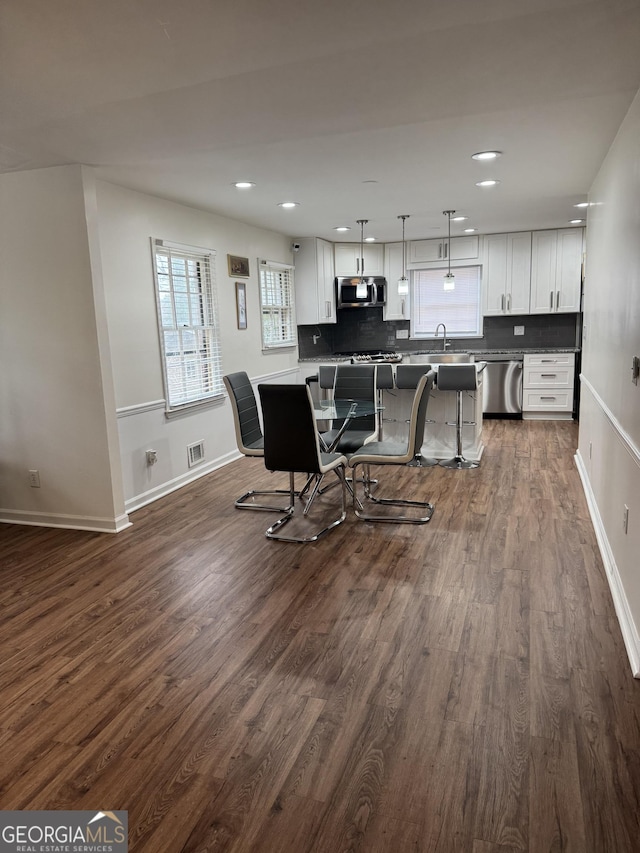 kitchen with stainless steel appliances, dark wood finished floors, a sink, and a kitchen island