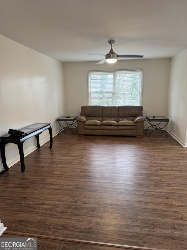 unfurnished living room featuring dark wood-type flooring, a ceiling fan, and baseboards