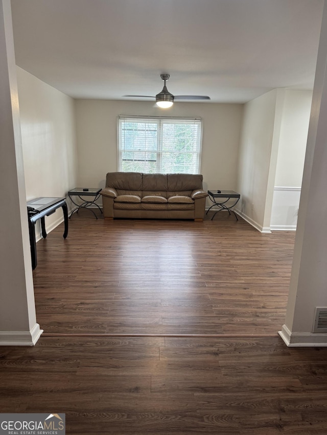 unfurnished living room featuring visible vents, dark wood finished floors, baseboards, and ceiling fan