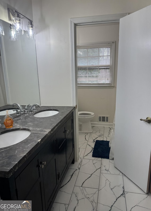 full bathroom with toilet, marble finish floor, a sink, and visible vents