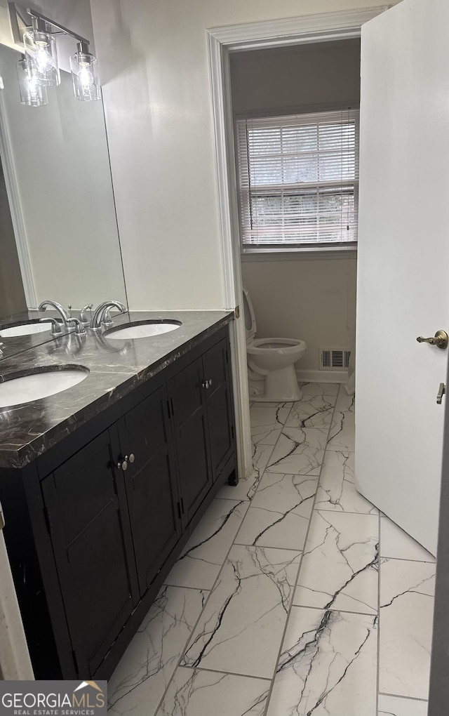 bathroom with double vanity, visible vents, toilet, marble finish floor, and a sink