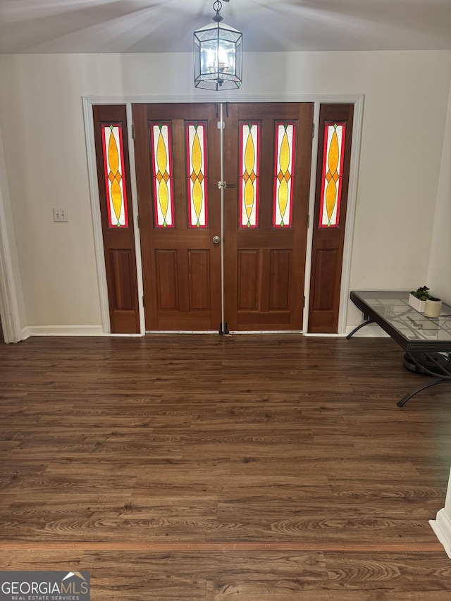 foyer entrance with baseboards, wood finished floors, and an inviting chandelier