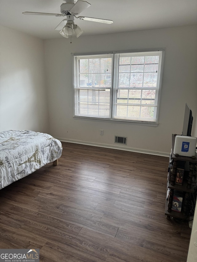 bedroom with multiple windows, visible vents, and dark wood finished floors