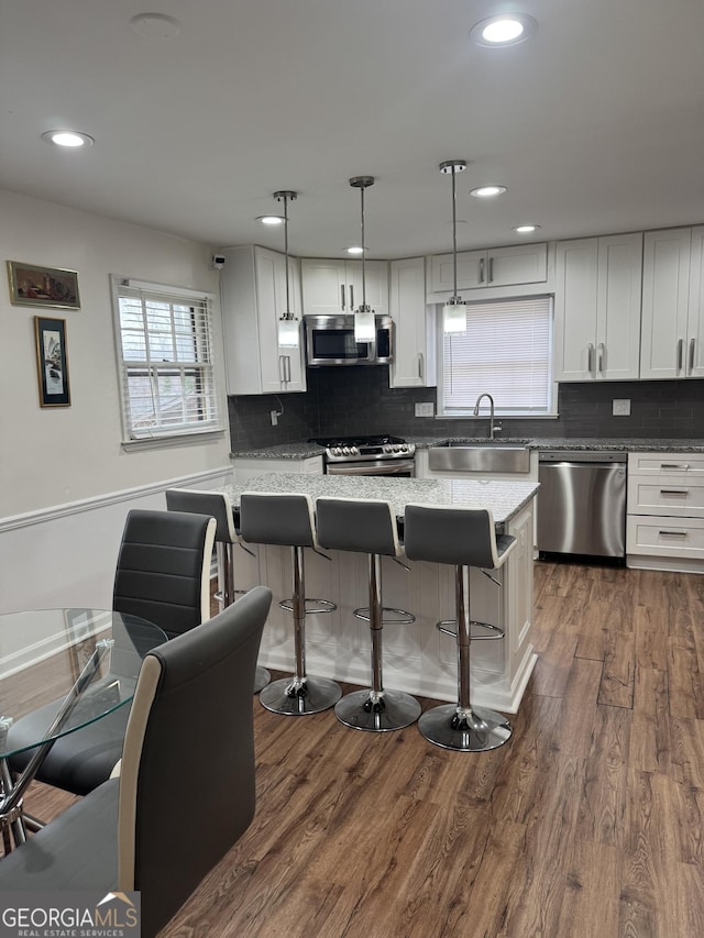 kitchen with dark wood-style floors, stainless steel appliances, a sink, and a kitchen breakfast bar