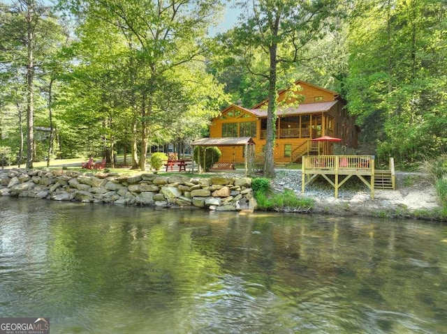 view of dock with a deck with water view and a wooded view