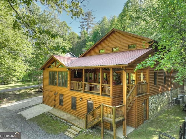 rear view of property with cooling unit, metal roof, driveway, and stairs