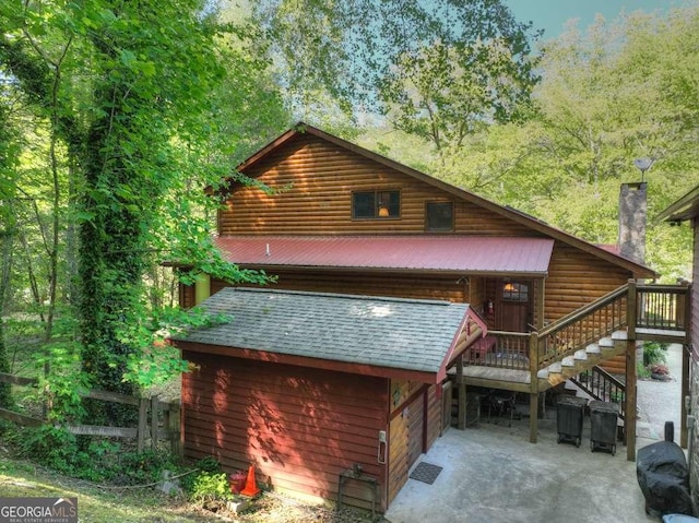 rear view of house with stairs, metal roof, a chimney, and a patio area