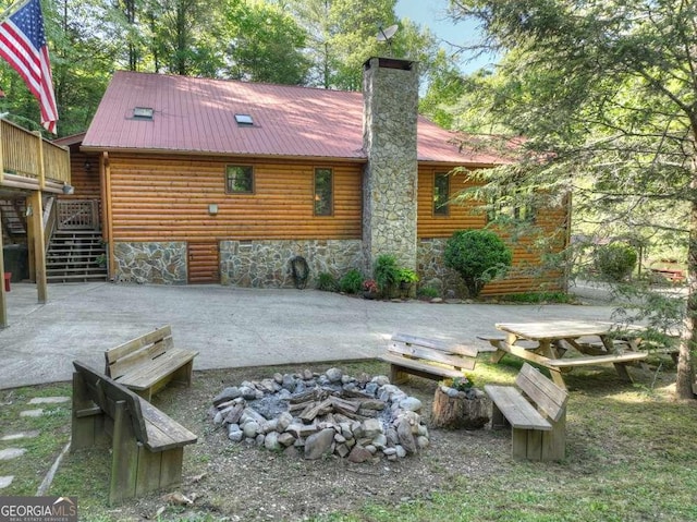 back of property featuring metal roof, a patio, a fire pit, stairs, and a chimney