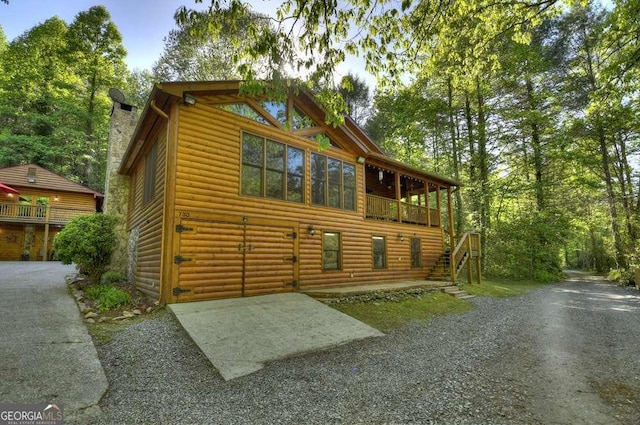 view of side of home featuring log veneer siding and stairs