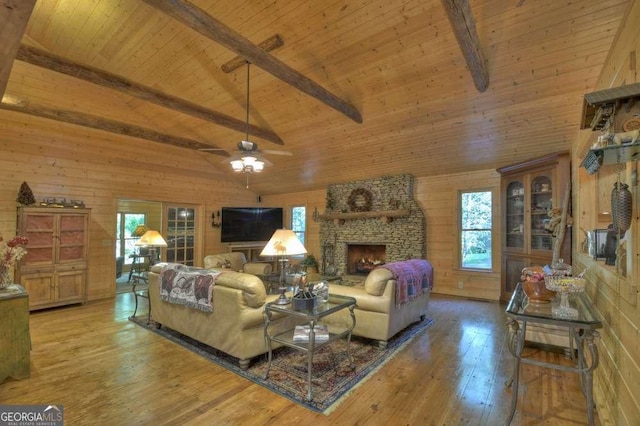 living room with lofted ceiling with beams, a stone fireplace, hardwood / wood-style flooring, wooden walls, and wood ceiling