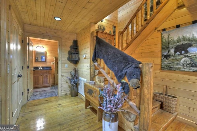 hall with wooden walls, wooden ceiling, wood-type flooring, and stairs