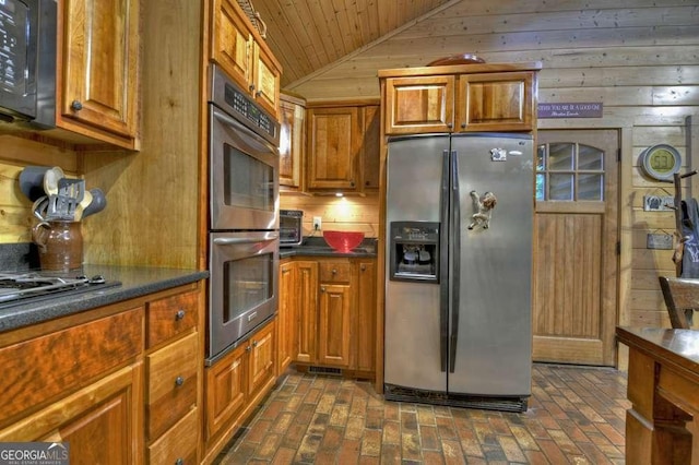 kitchen featuring dark countertops, brown cabinets, vaulted ceiling, and black appliances