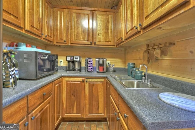 kitchen with stainless steel microwave, brown cabinetry, and a sink