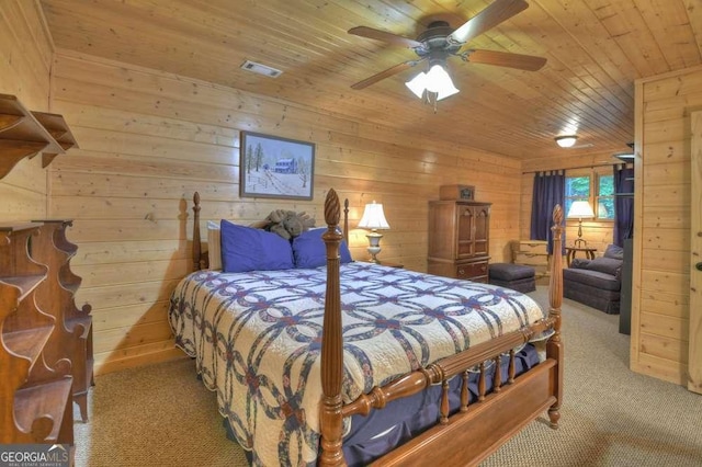 carpeted bedroom featuring visible vents, ceiling fan, wood walls, and wood ceiling