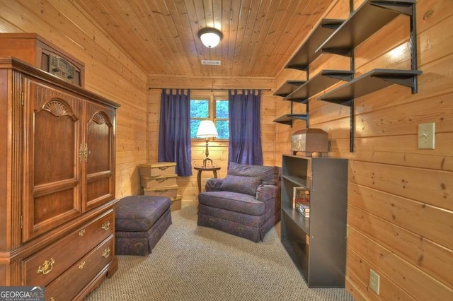 sitting room with wood walls, wood ceiling, visible vents, and carpet flooring