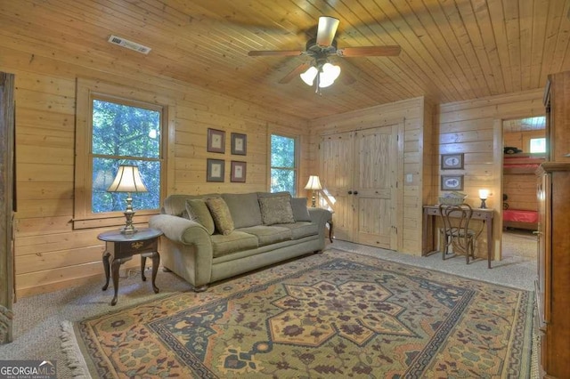 living room featuring visible vents, carpet flooring, wood walls, ceiling fan, and wooden ceiling