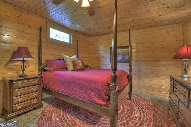 carpeted bedroom featuring a ceiling fan, wood ceiling, and wooden walls