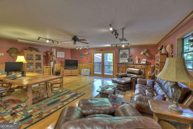 living area featuring wood-type flooring, ornamental molding, a wealth of natural light, and wainscoting