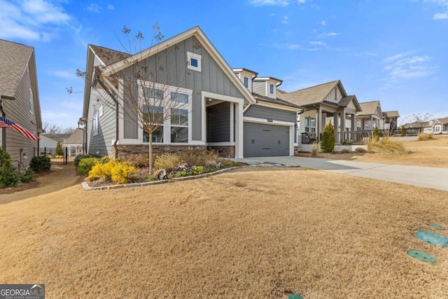 craftsman-style house featuring an attached garage, driveway, stone siding, a front lawn, and board and batten siding