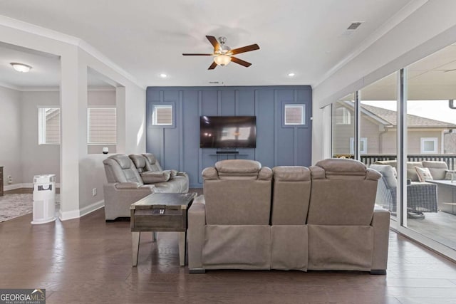 living room with visible vents, a decorative wall, dark wood-type flooring, ornamental molding, and baseboards