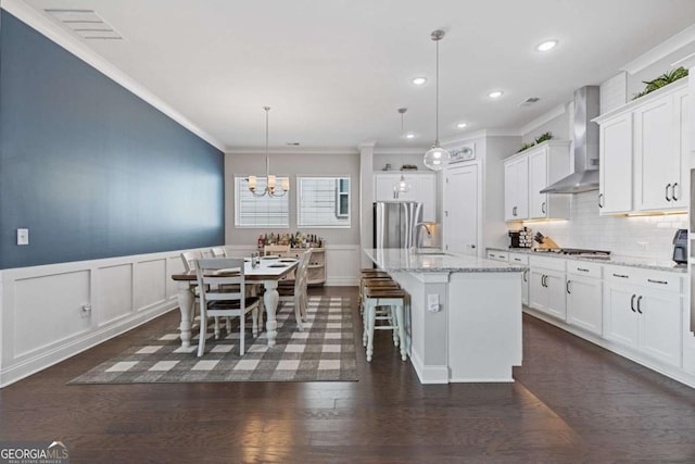 kitchen with dark wood-style flooring, a sink, white cabinets, appliances with stainless steel finishes, and wall chimney exhaust hood